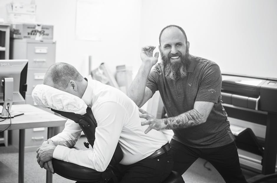 Professional massage therapist performs seated massage on man in office.